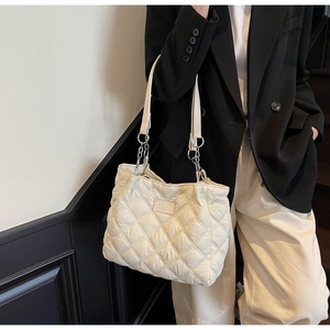 Detailansicht der beigefarbenen Stepptasche mit Silberketten und minimalistischer Textur