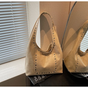 Détails des rivets argentés et texture du cuir plissé sur un sac hobo beige chic