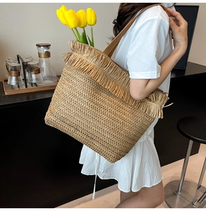 Detailed close-up of woven straw tote bag featuring dense tassel fringe trim and texture