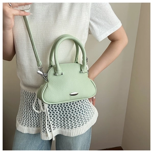 Detail of mint green pebble leather shell bag with adjustable strap and metal hardware