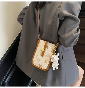 Chic cream and brown crossbody phone bag with Keddy Bear logo worn over a grey blazer