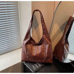 Gros plan détaillé du sac cabas marron vintage avec rivets métalliques et cuir texturé
