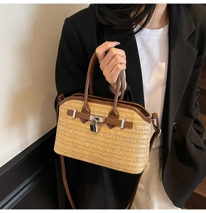 Detailed view of woven straw handbag featuring brown leather trim and silver metal lock