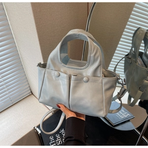 Detail of blue faux leather tote bag with front pockets and detachable strap in a room setting
