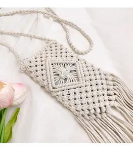 Detail of handmade cream macrame bag with diamond knit patterns and long tassels