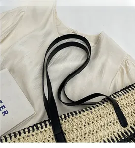 Détail d'un sac cabas tissé beige et noir avec de fines poignées en cuir noir