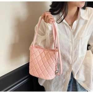 Dettaglio borsa a secchiello rosa trapuntata con ciondolo argento e cuciture di classe