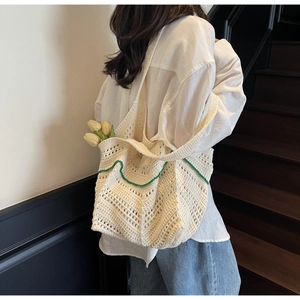 Detail view of beige handmade crochet tote bag with contrast green wavy edge