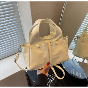 Detail of cream white faux leather tote bag with dual front pockets and top handle