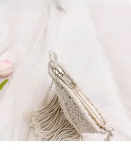 Macro view of a smooth metal zipper closure on a white woven macrame straw handbag