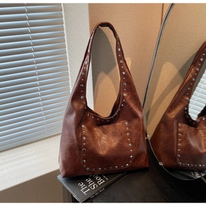 Détails du sac hobo marron vintage avec rivets argentés et texture en cuir lisse