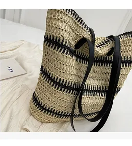 Détail du sac cabas en paille tissée avec rayures noires et anses d'épaule en cuir noir