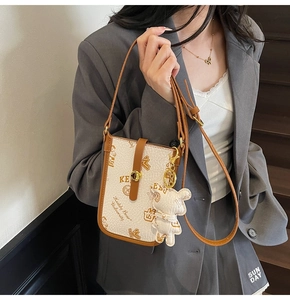 Close-up of retro printed shoulder bag with teddy bear charm and adjustable strap