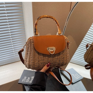 Close-up of woven straw handbag with bamboo handle and golden twist-lock closure