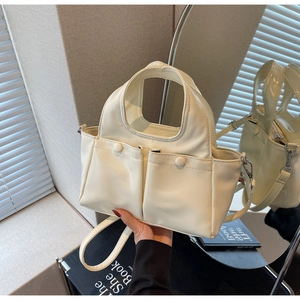 Detail of cream tote bag with dual front button pockets and detachable long strap