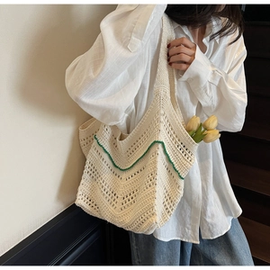 Handmade cream crochet tote bag with green wavy trim worn with casual white shirt
