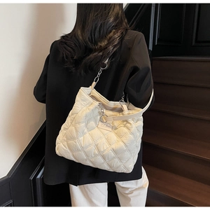 Detail der weißen Stepp-Tote-Bag mit silberner Kette über einem schwarzen Blazer