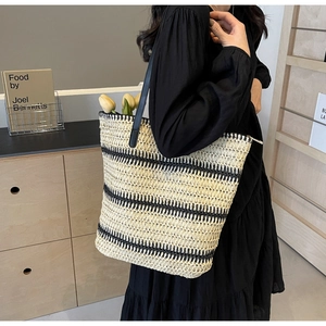 Détail du sac cabas tissé à rayures crème et noir avec des bandoulières en cuir