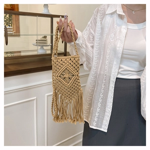 Detail of bohemian straw phone bag with tassel trim and woven diamond patterns