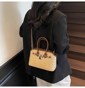 Detail of woven straw handbag featuring brown leather straps and silver padlock detail