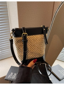 Minimalist straw weave bucket bag with black leather trim and adjustable shoulder strap