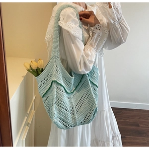 Close-up of mint blue knit tote bag showing intricate hollow crochet texture and V-pattern