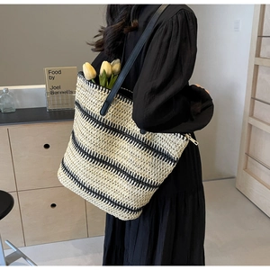 Détail d'un cabas tissé rayé avec poignées en cuir et fermeture éclair sur le dessus