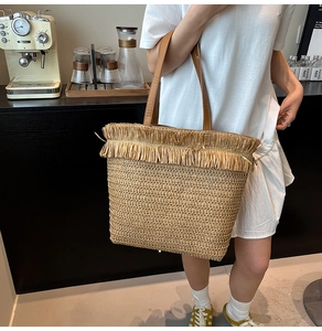 Detail of hand-woven straw tote bag with long tassels and brown leather handles