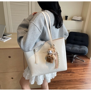 Detail of white crocodile pattern tote bag with teddy bear charm and silk scarves