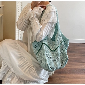 Detail of light blue handmade crochet tote with green wave pattern in a lifestyle setting