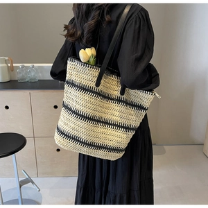 Détail du sac cabas tissé avec rayures beiges, lanières en cuir noir et fermeture éclair