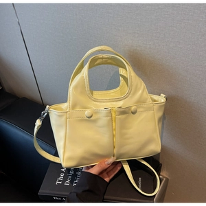 Close-up of glossy yellow patent leather tote bag with functional double front pockets