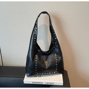 Détail d'un sac hobo noir en cuir avec rivets argentés et large bandoulière épaule