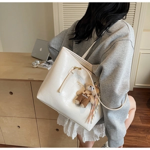 Crocodile pattern white tote bag on model's shoulder with cute bear pendant charm