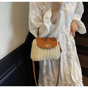 Detail of woven straw bag with bamboo handle and leather flap on white dress