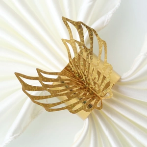 Detailed macro view of golden laser-cut butterfly napkin ring with glitter on white satin
