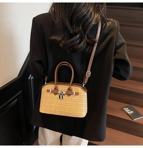 Detail of a beige woven straw handbag with dark brown leather trim and silver clasp lock