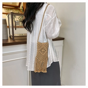 Detail of hand-woven straw crossbody bag with fringe tassels and diamond knit pattern