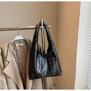 Détail des rivets en métal argenté sur un sac porté épaule hobo en cuir noir vintage