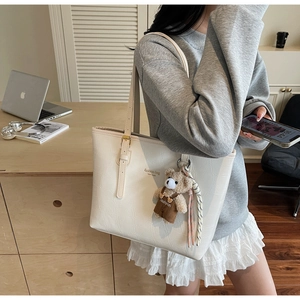 Detail of cream croc-effect tote bag with fashion lettering and cute bear charm