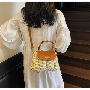Detail of woven straw crossbody bag with bamboo handle and golden lock mechanism
