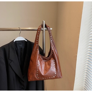 Détail d'un sac hobo marron vintage avec rivets argentés sur un support en métal