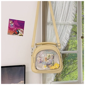 Detail of beige PU leather Itabag with transparent window displaying anime badges and pins
