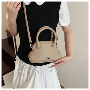 Close-up of beige lychee grain leather shell bag with elegant oval silver hardware