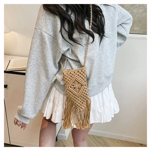 Close-up of bohemian macrame woven crossbody bag with long tassels for summer beach style