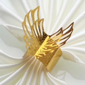 Close-up of golden butterfly napkin ring with glitter hollow design on white satin fabric