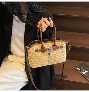Fashionable woven straw handbag with brown leather trim and silver metal twist lock detail