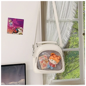 Detailed view of white ita bag featuring a large transparent window and dog plush accessory