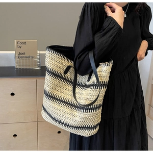 Détail d'un grand sac cabas en paille tissée à rayures noires et beiges sur un mannequin