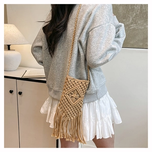Detail shot of bohemian woven cotton phone bag with fringe trim on a crossbody strap